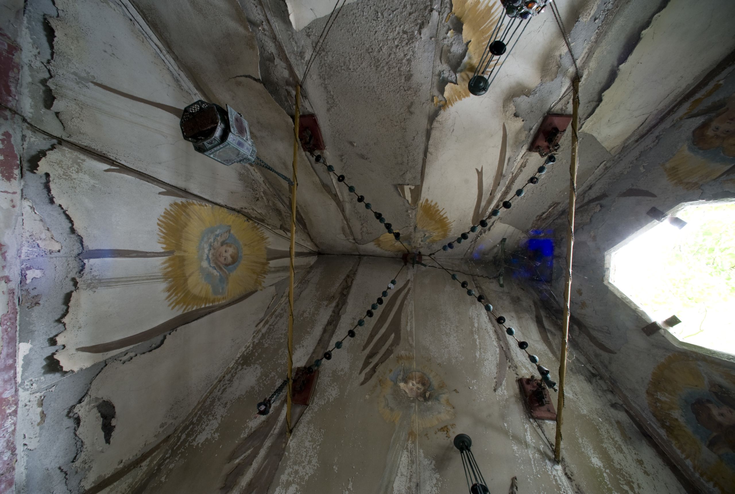 The mausoleum's ceiling, with painted Catholic iconography and camel bells