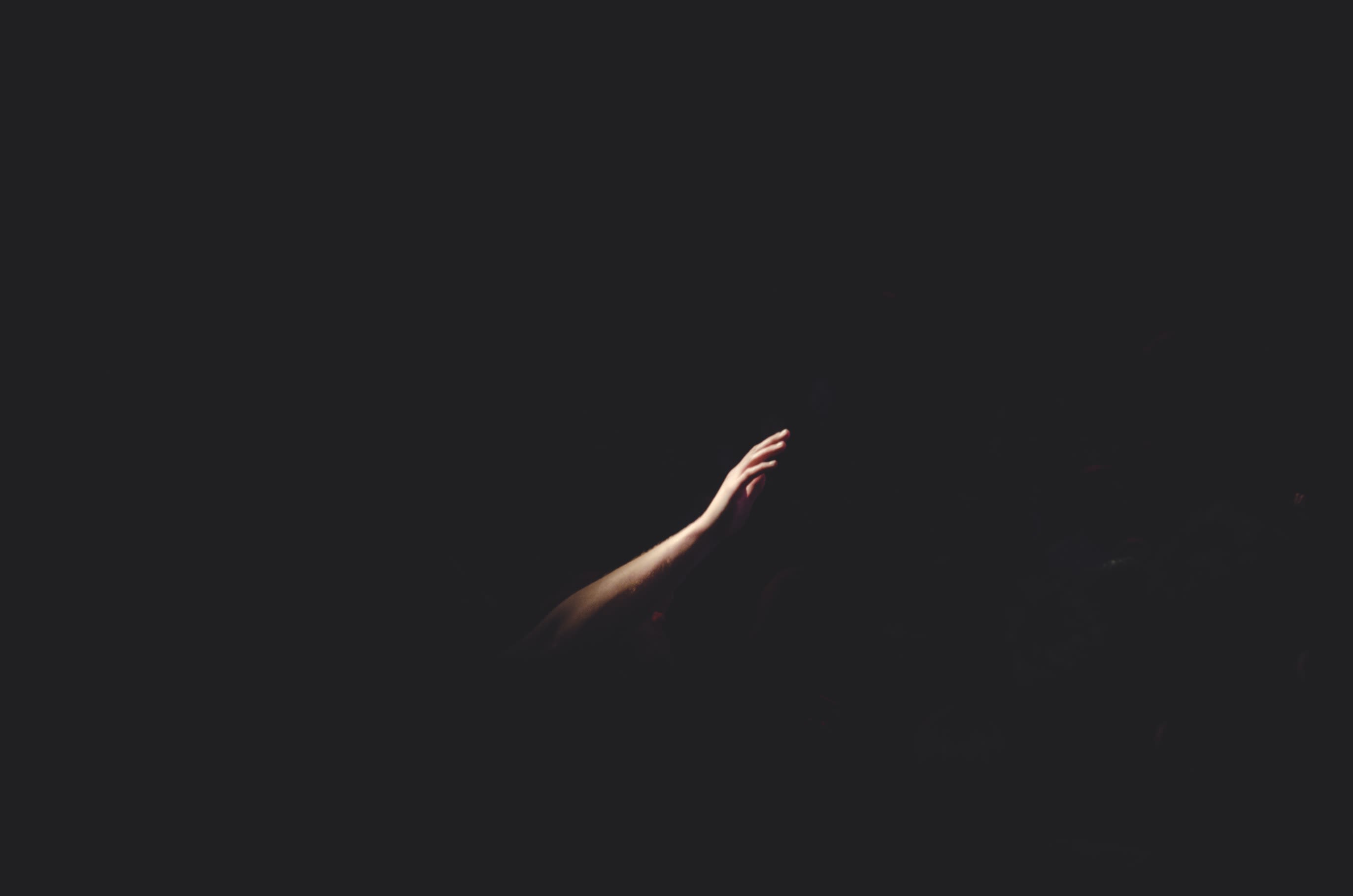 Hand reaching out for help in the darkness