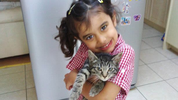 Aamina Khan smiling at the camera as she hugs her cat.