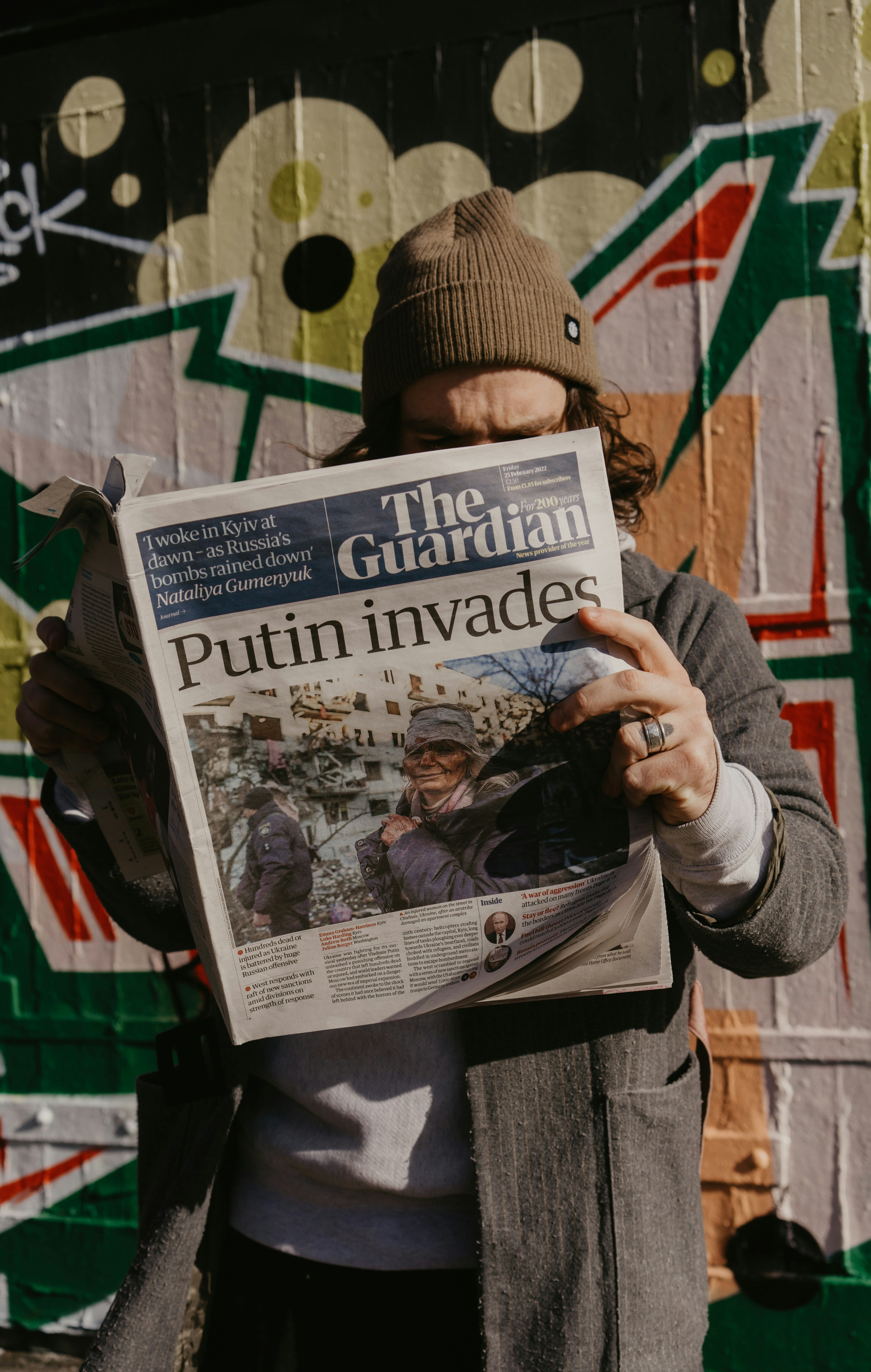 a person standing in front of a wall with a newspaper