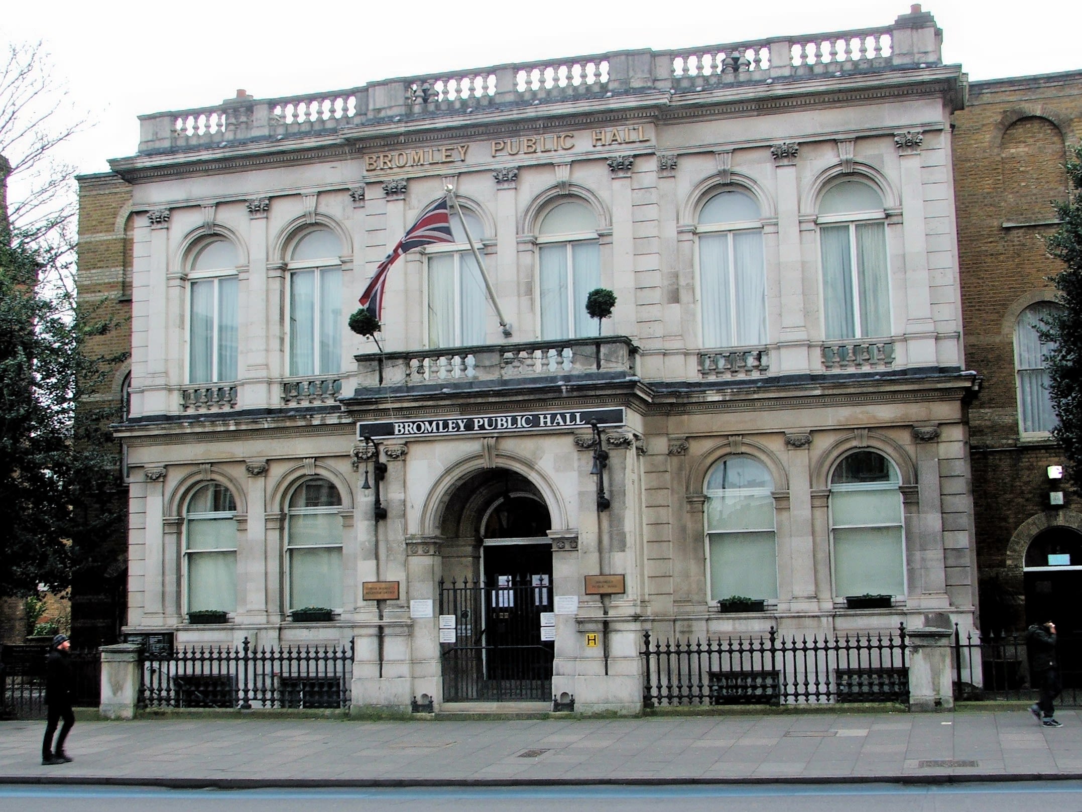 The washed out white stone facade of Bromley Public Hall with the UK flag flying in front