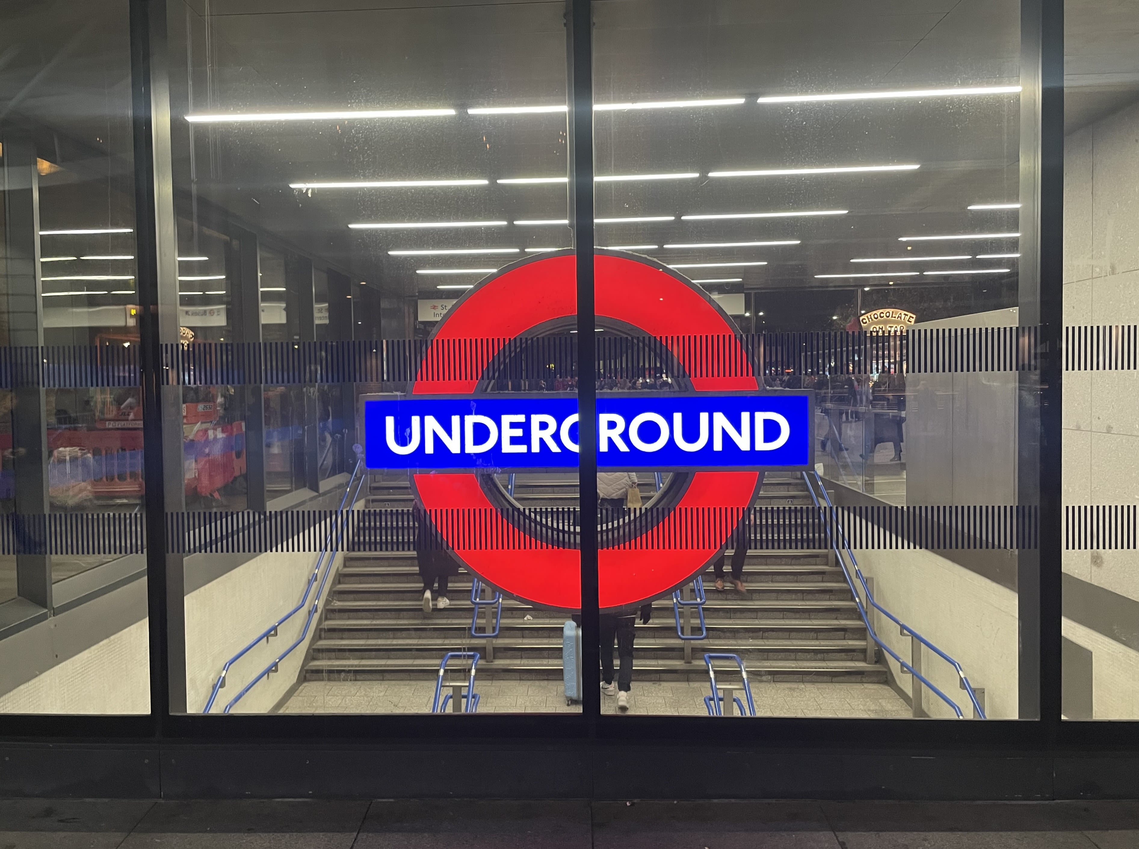 Lit London Underground sign behind glass