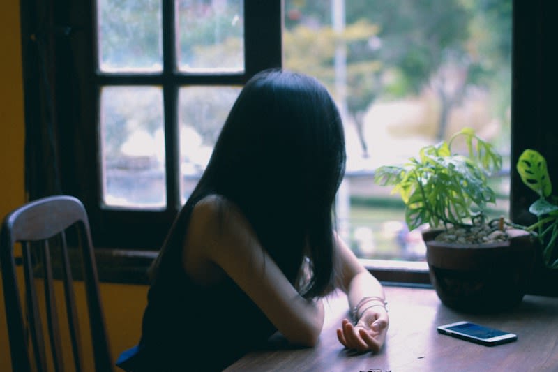 A woman sitting at a table staring outside.