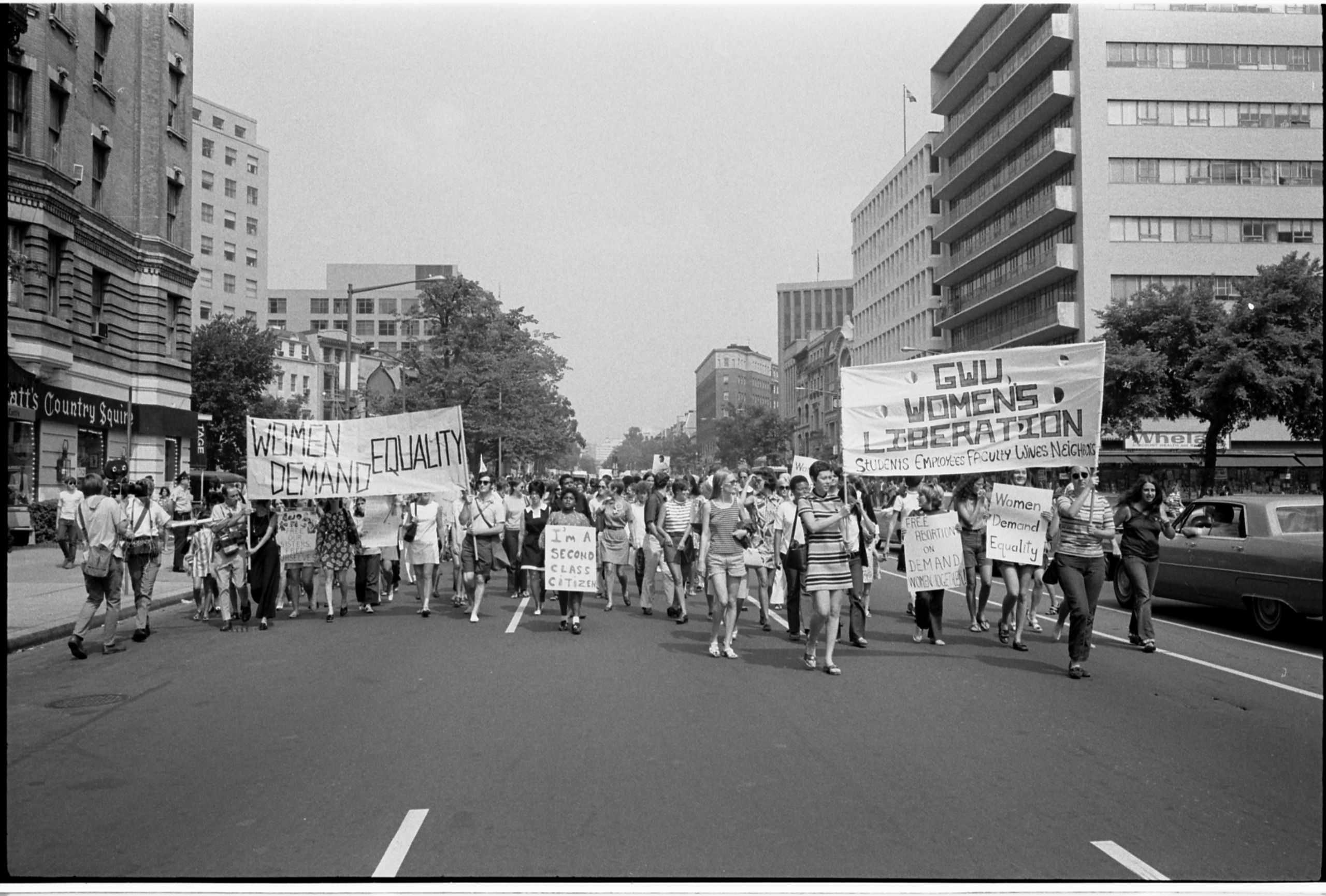 Women marching in protest holding banners reading 'Women Demand Equality'