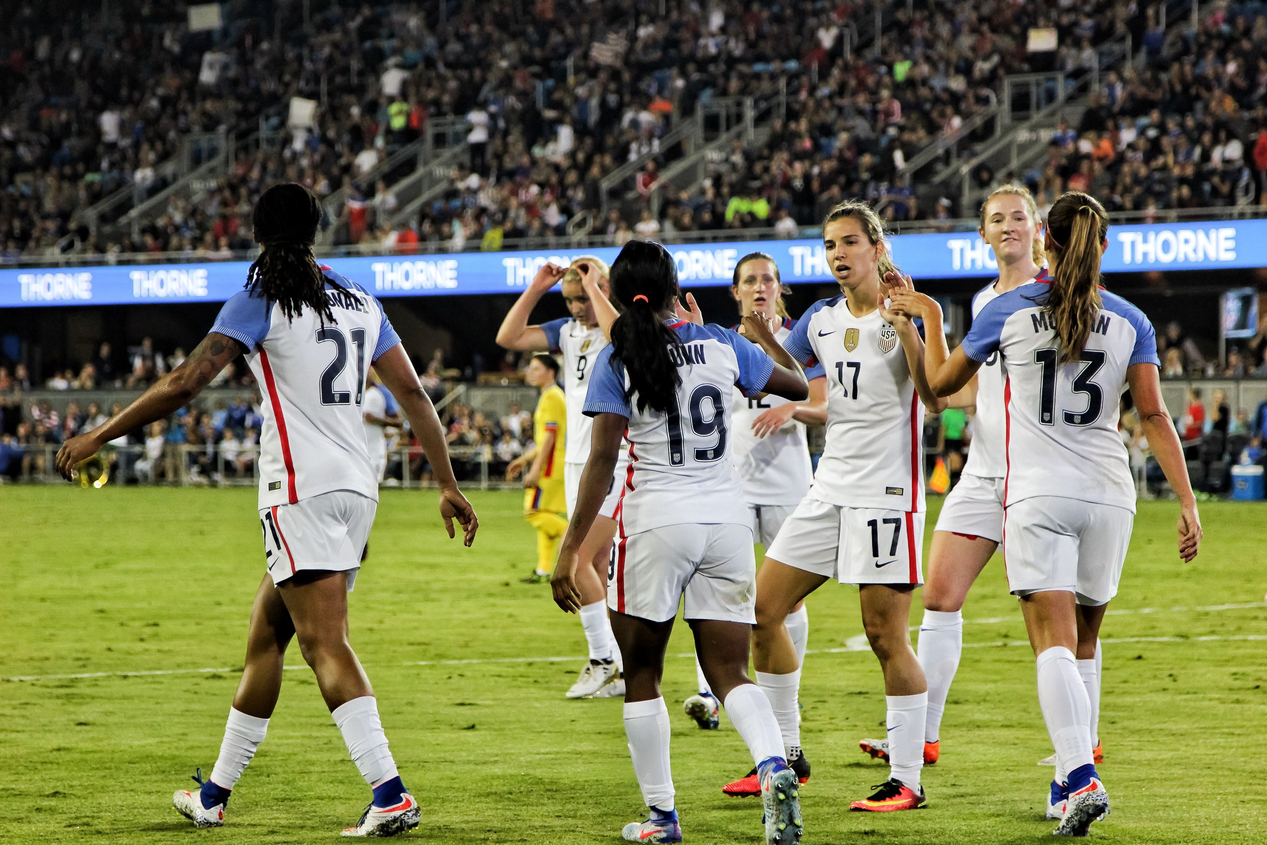 female soccer players at the field near people on bleachers