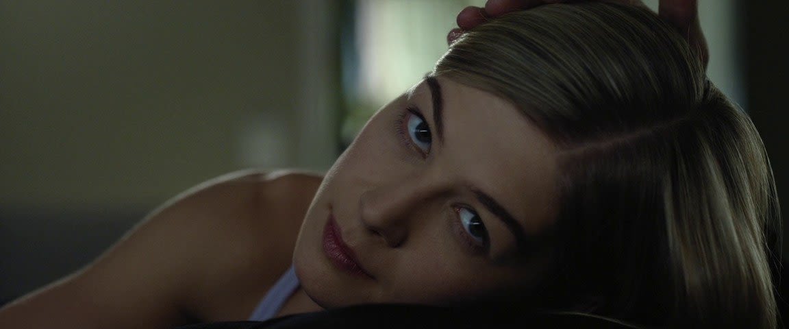 ShorthandRosamund Pike, lying down, looks at camera with hand on her head