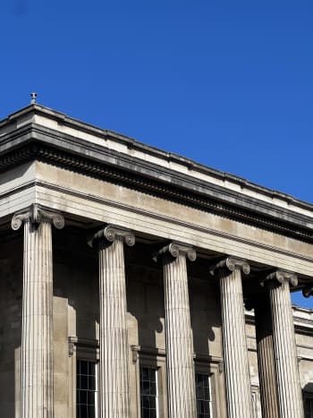 A photo of the pillars of the British museum against a blue sky