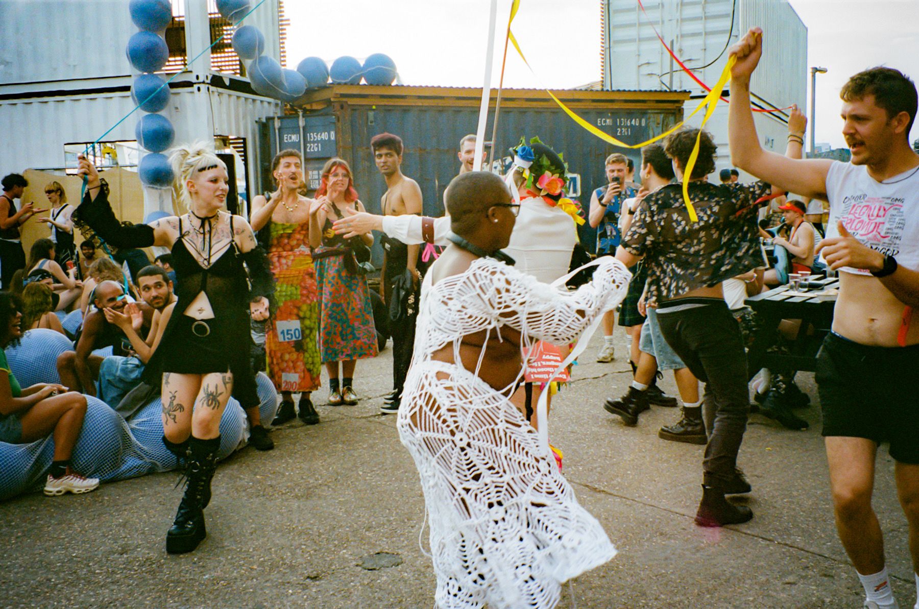 Group of people watch as another group dance around a maypole