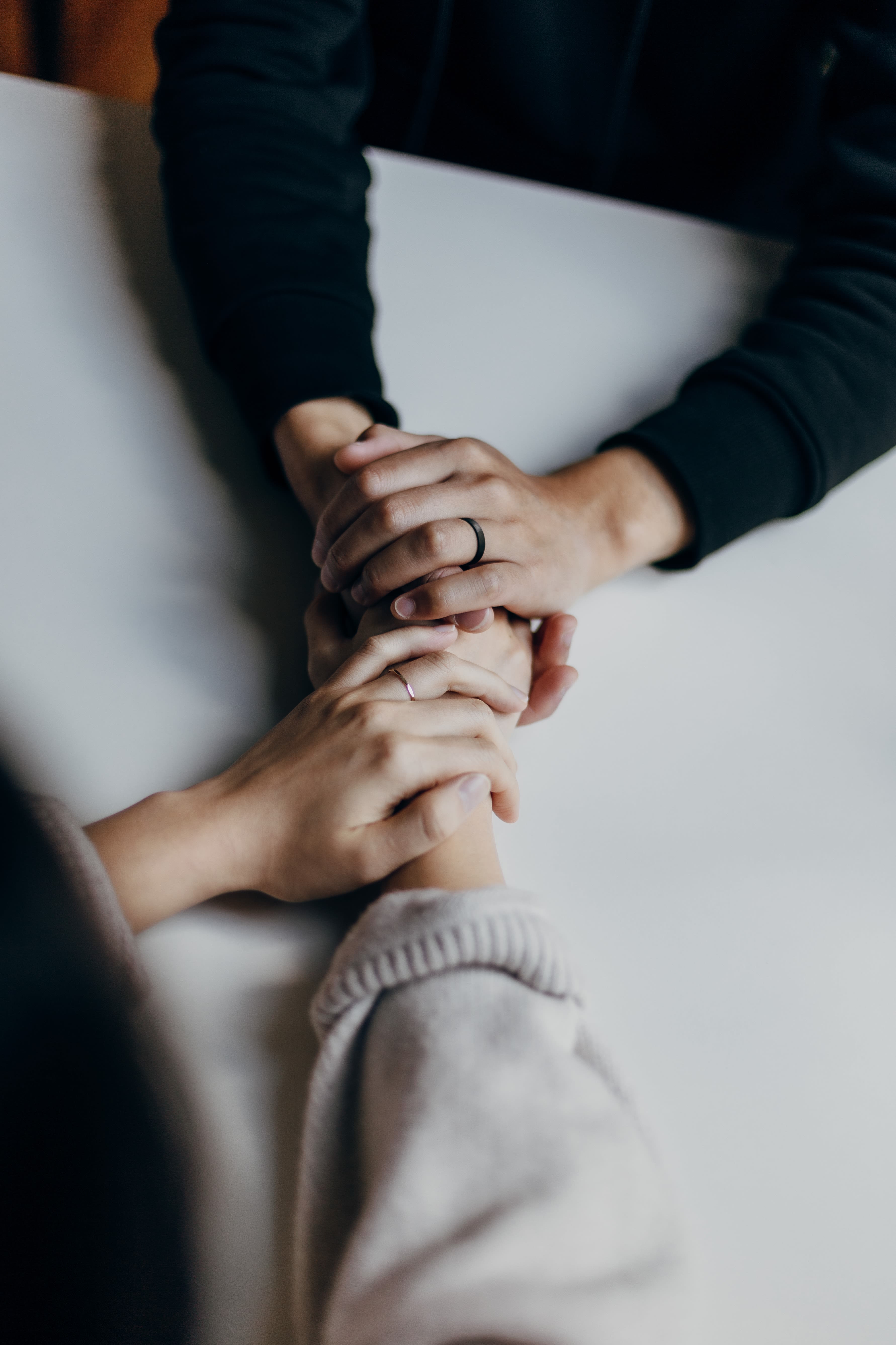 person in black long sleeve shirt holding hand of person in white jumper