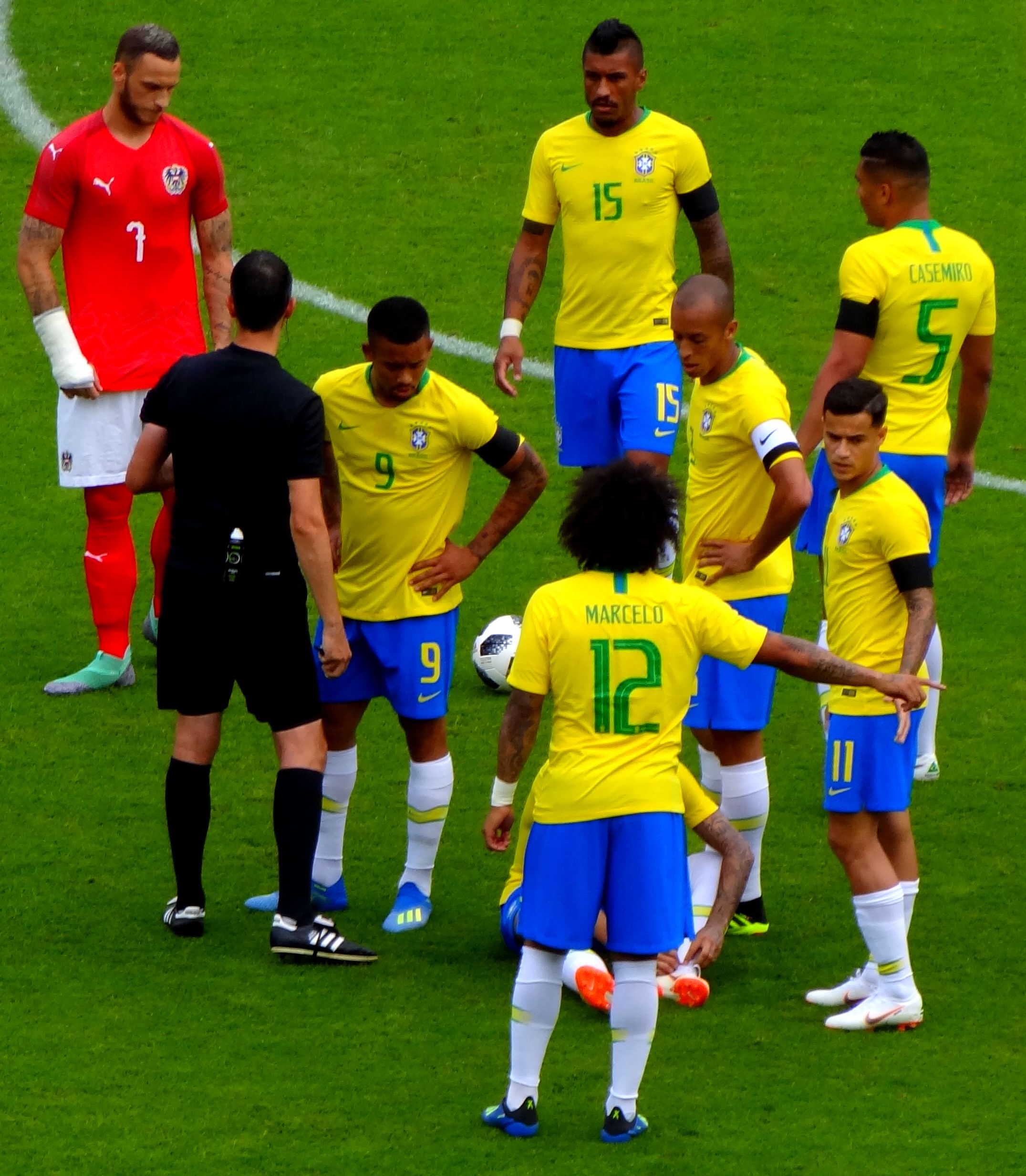 Group of Brazilian players in yellow shirts surrounding Neymar who is injured on the floor next to referee in match against Austria