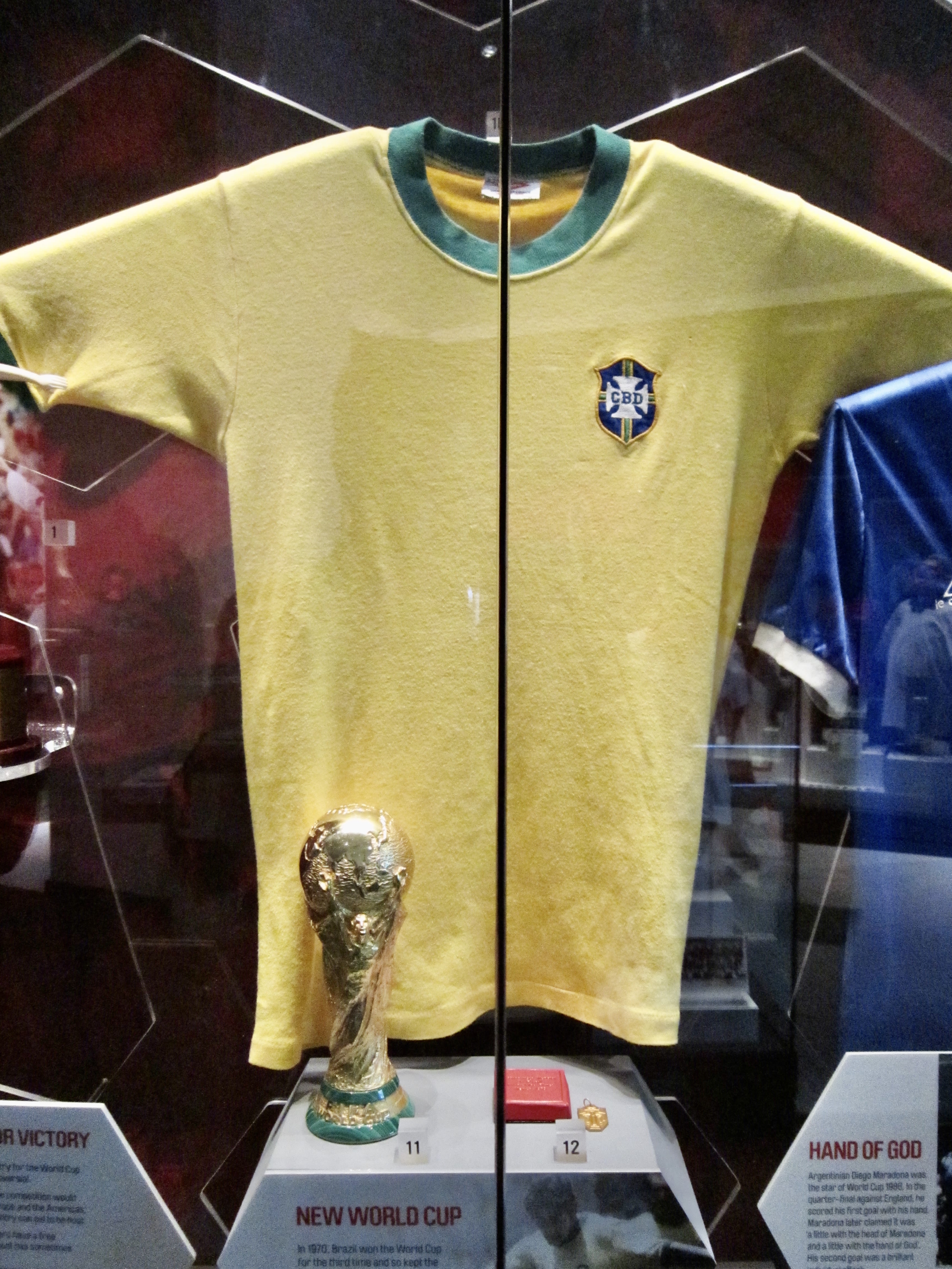 Yellow Brazil shirt in a museum with the World Cup trophy in front of it