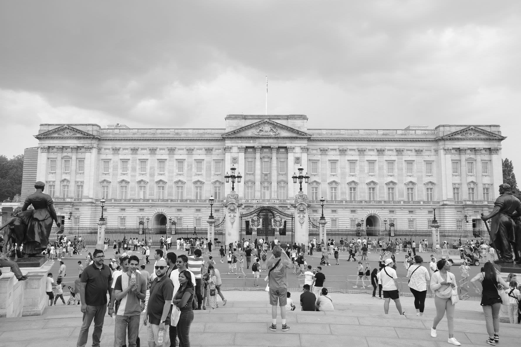 Full close-up view of Buckingham Palace with tourists wandering outside it.