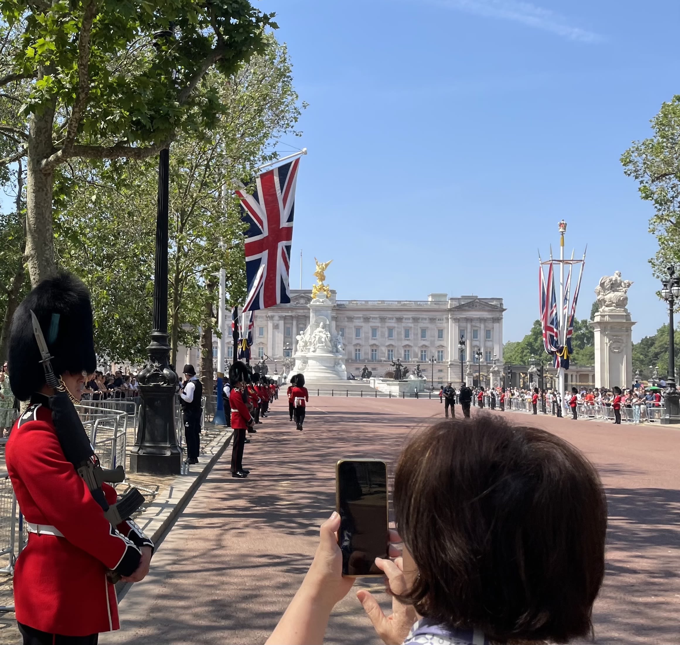 A woman takes a photo of a grenadier guard wearing a bearskin cap