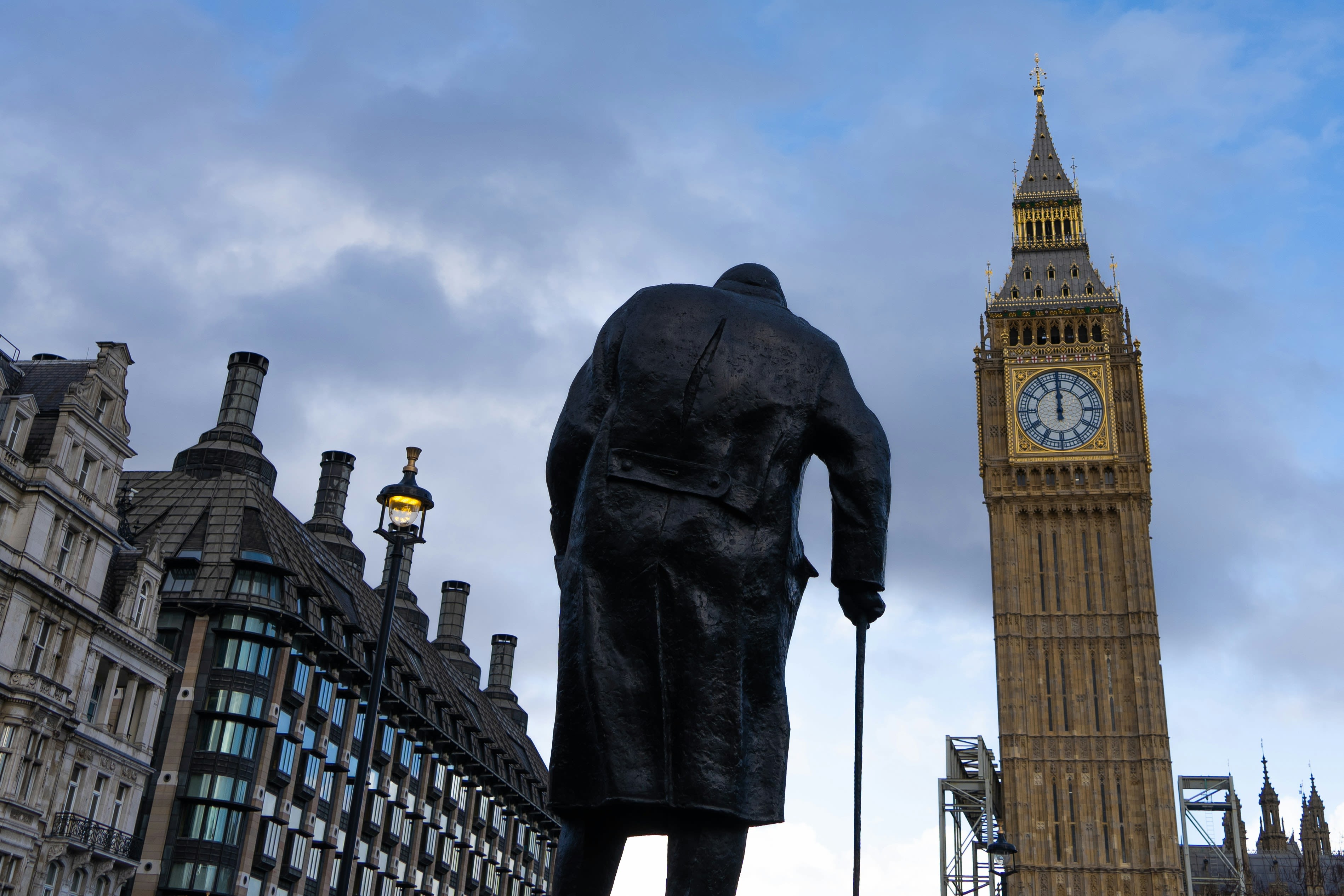 An image of London. Statue of the back profile of Winston Churchill in the centre facing Big Ben on the right