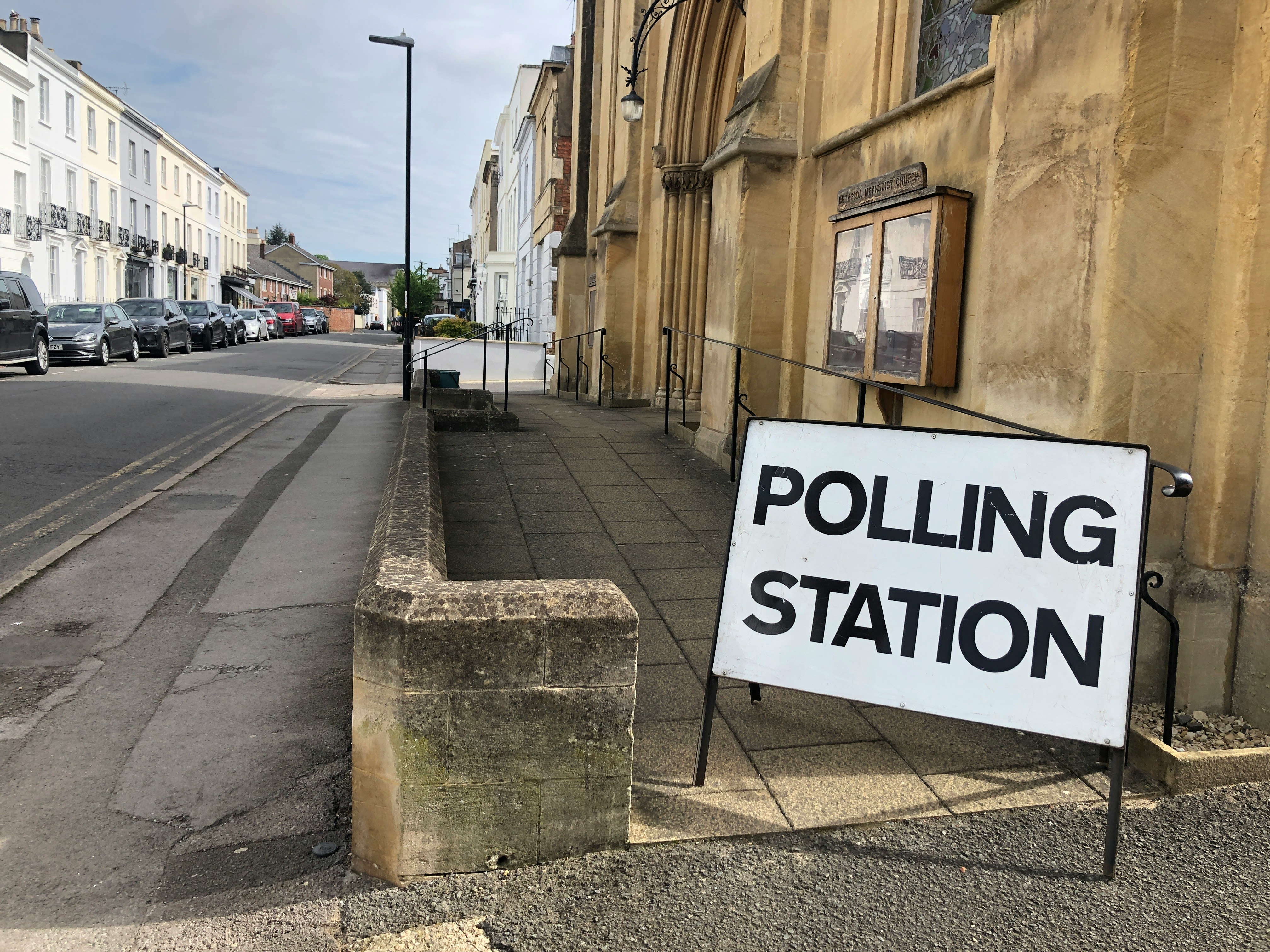 An entrance into an old building with a polling station sign positioned in front on the right side.
