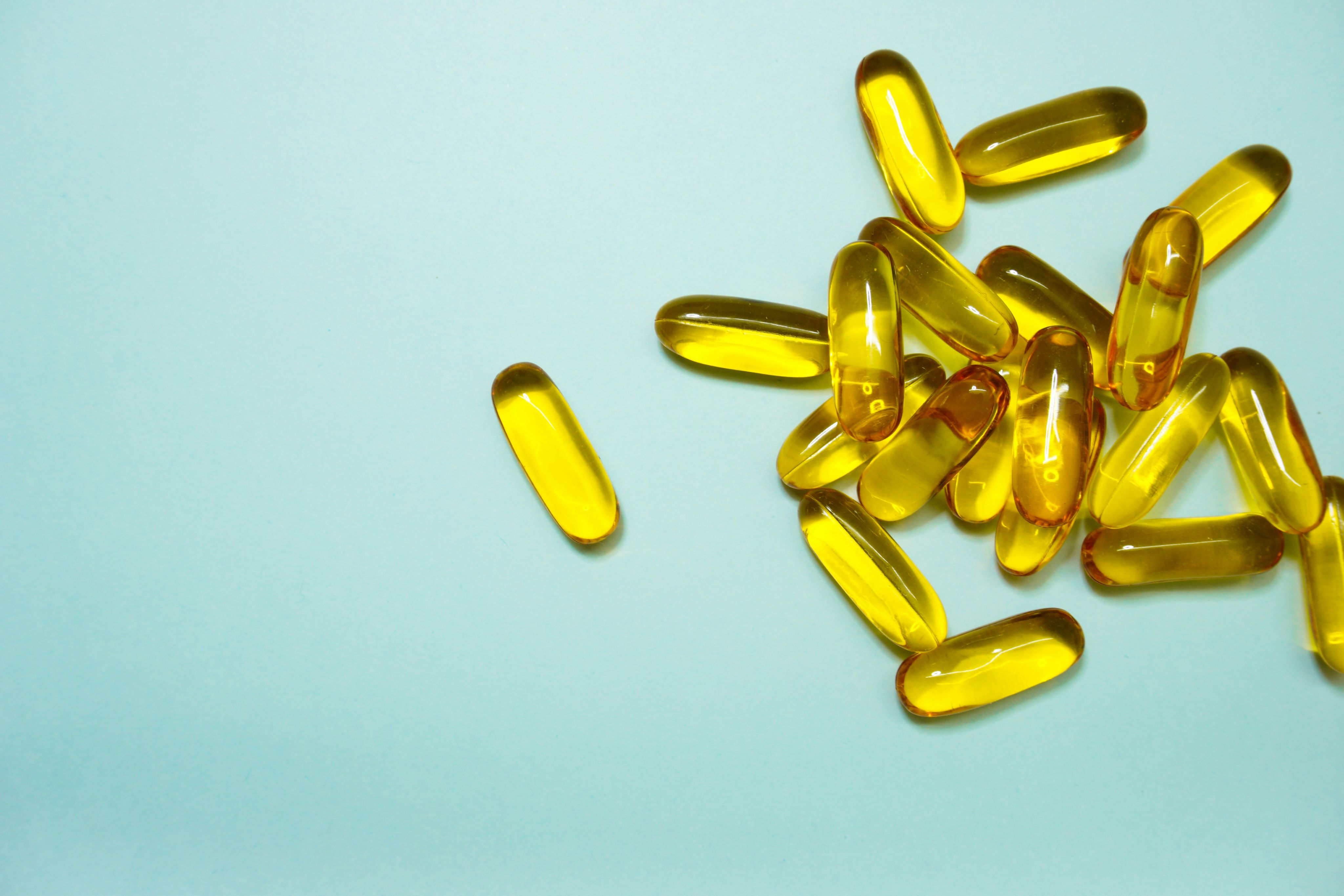 A cluster of transparent yellow pills on a light blue background