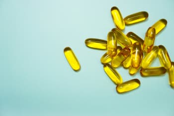A cluster of transparent yellow pills on a light blue background