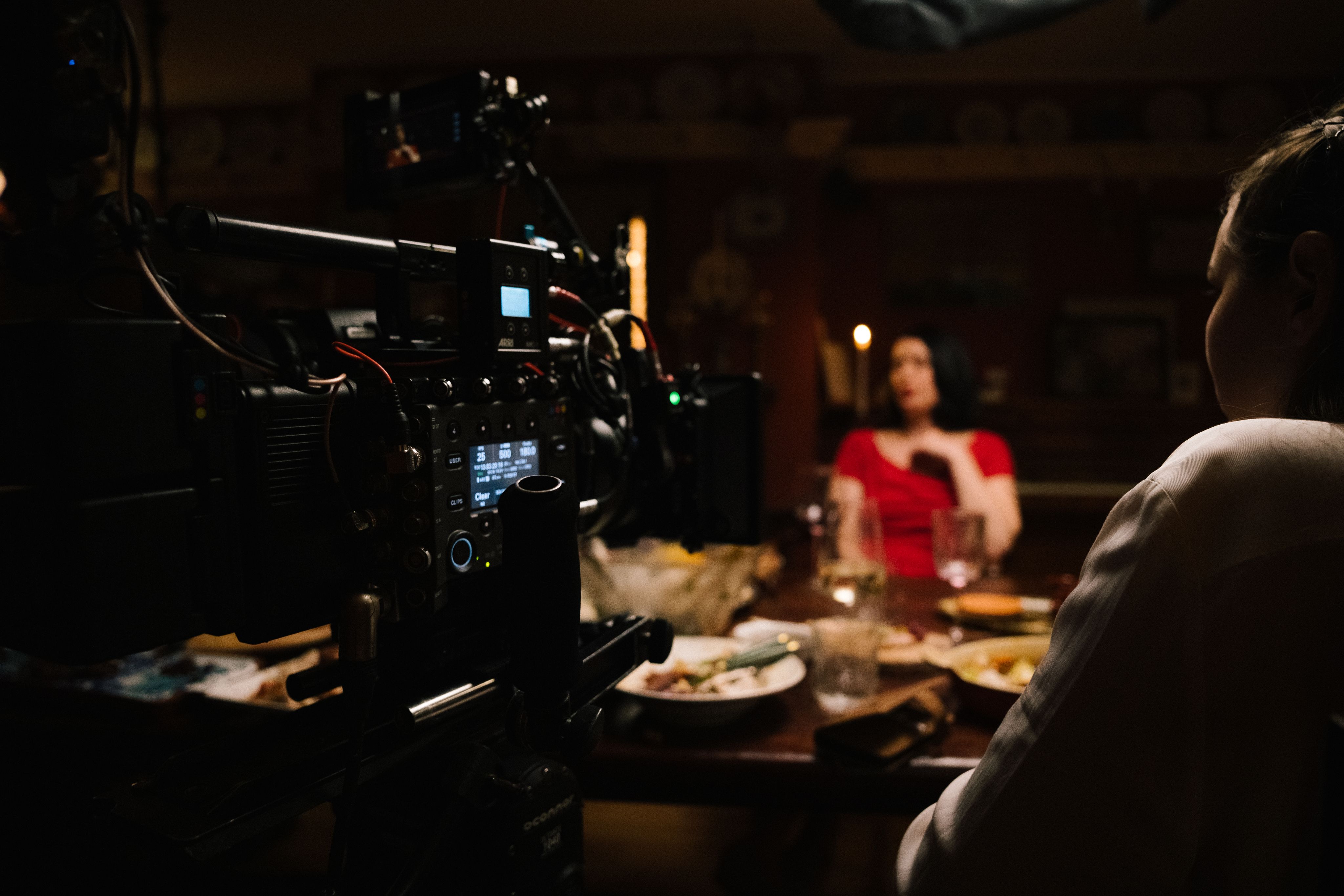 One women in shot of a camera with a woman sat behind the camera