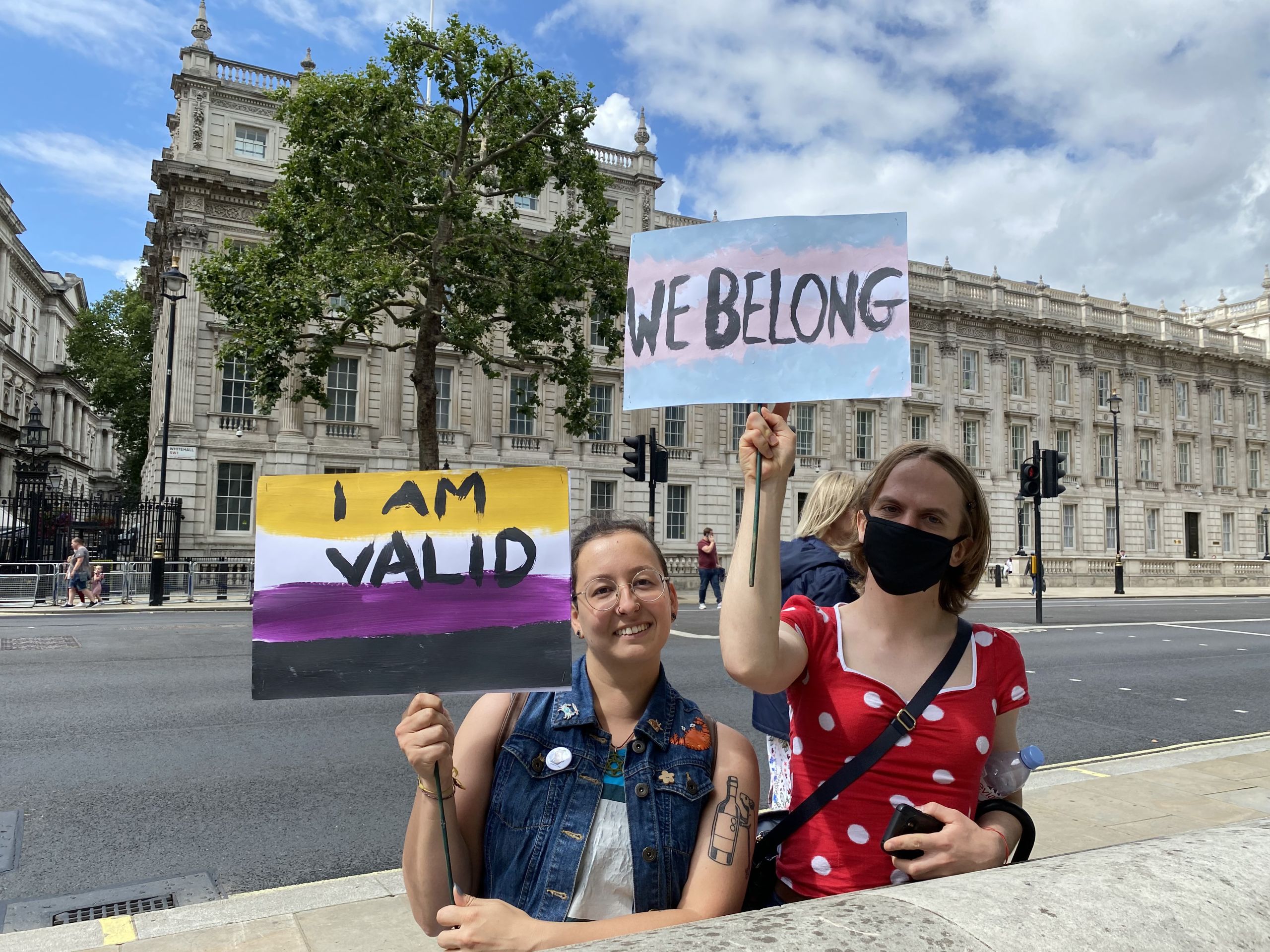 Lorelei and Nik holding "I am valid" and "We belong" signs