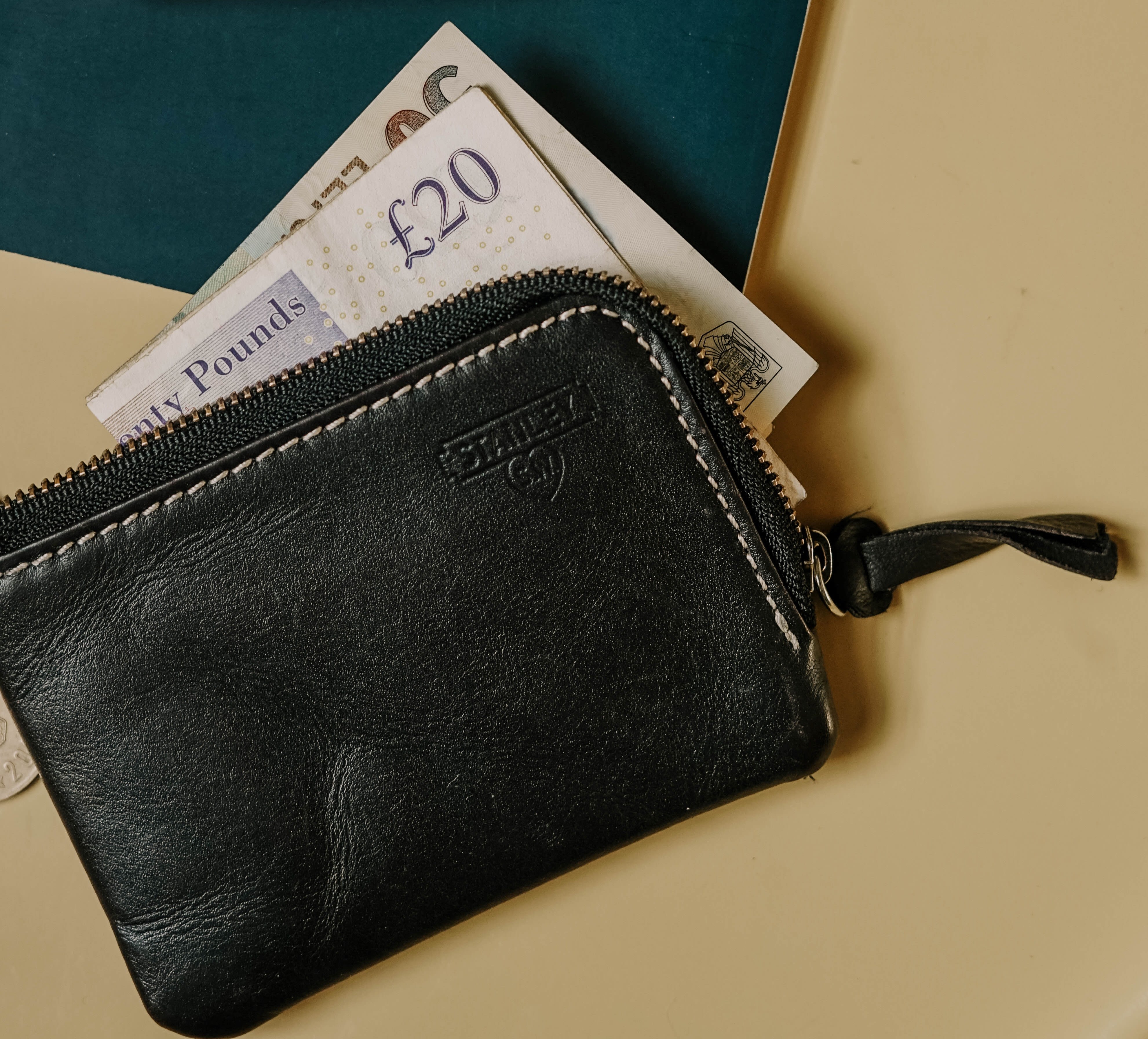 A background imag of a wallet with a £20 note inside