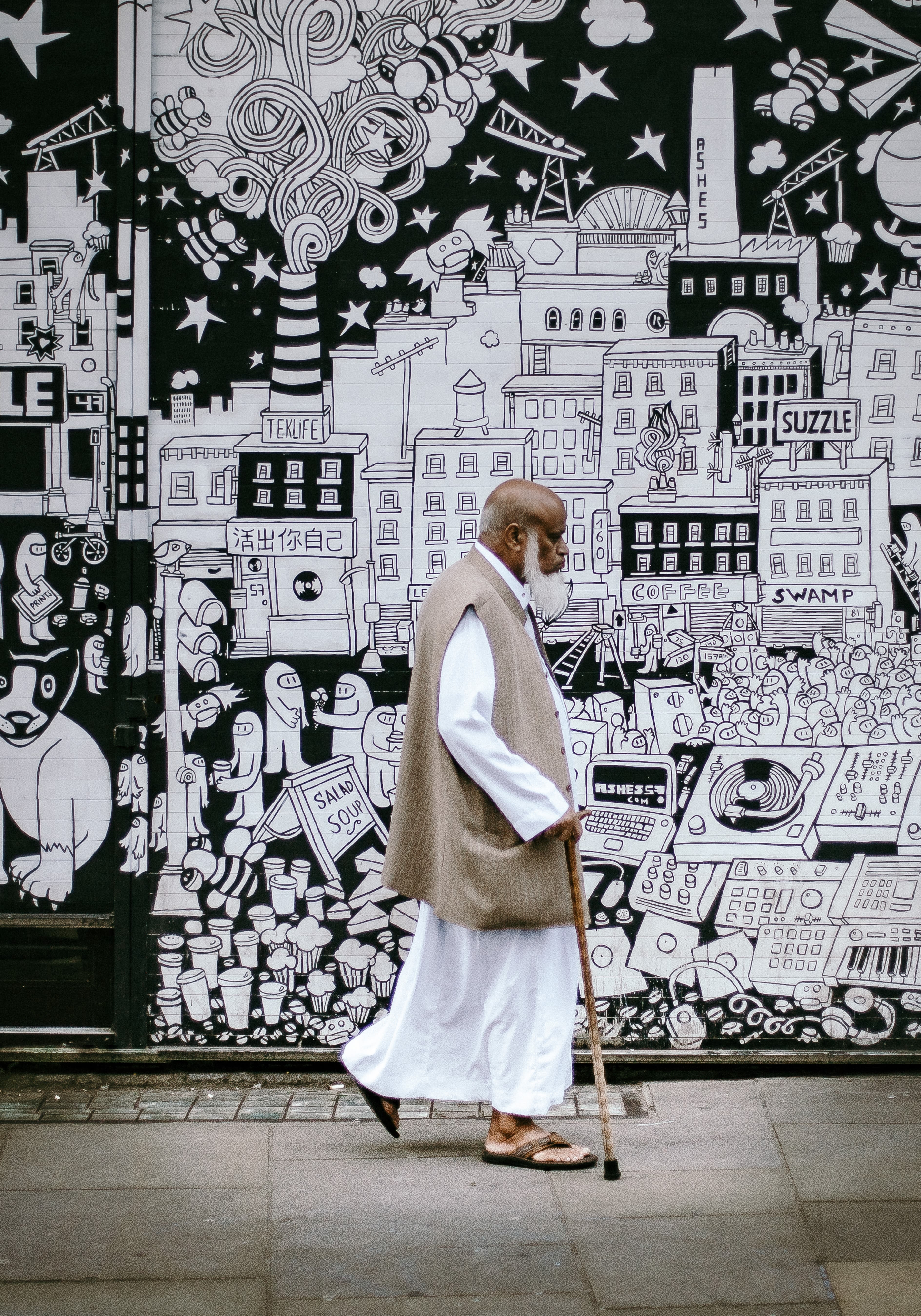 man wearing white sherwani robe beside graffiti