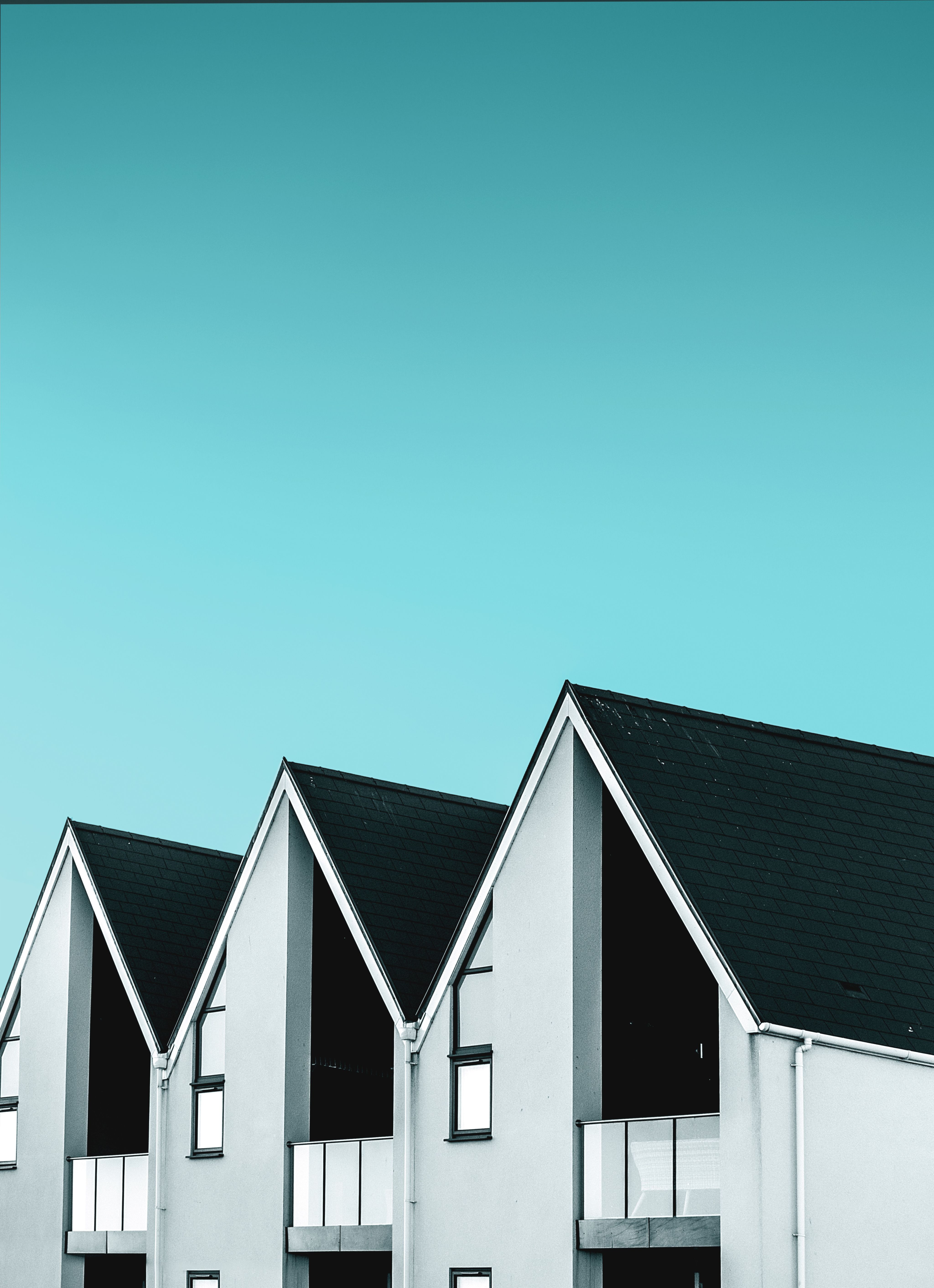 The roofs of three houses in a row with blue sky in the background